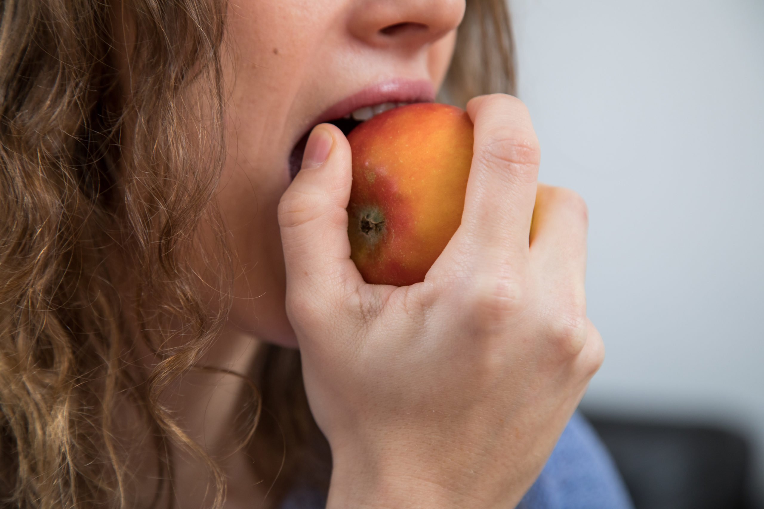 A woman bites into an apple.
