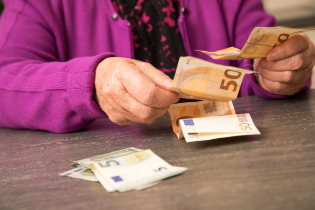 An elderly woman counts money.