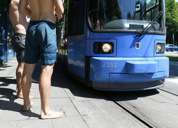Swimmers stand at the tram stop Tivolistraße in Munich.