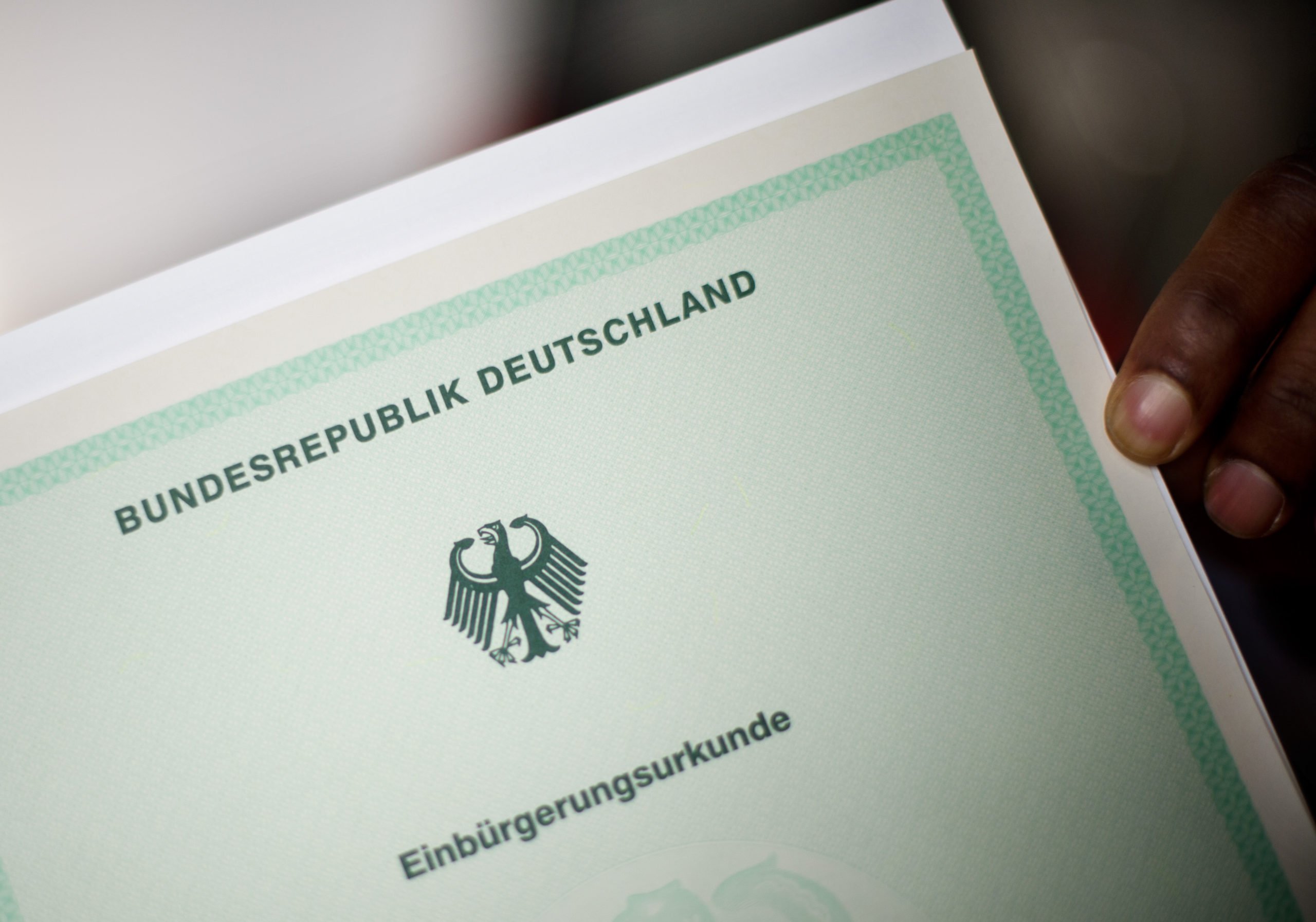 A man holds a German naturalisation certificate.