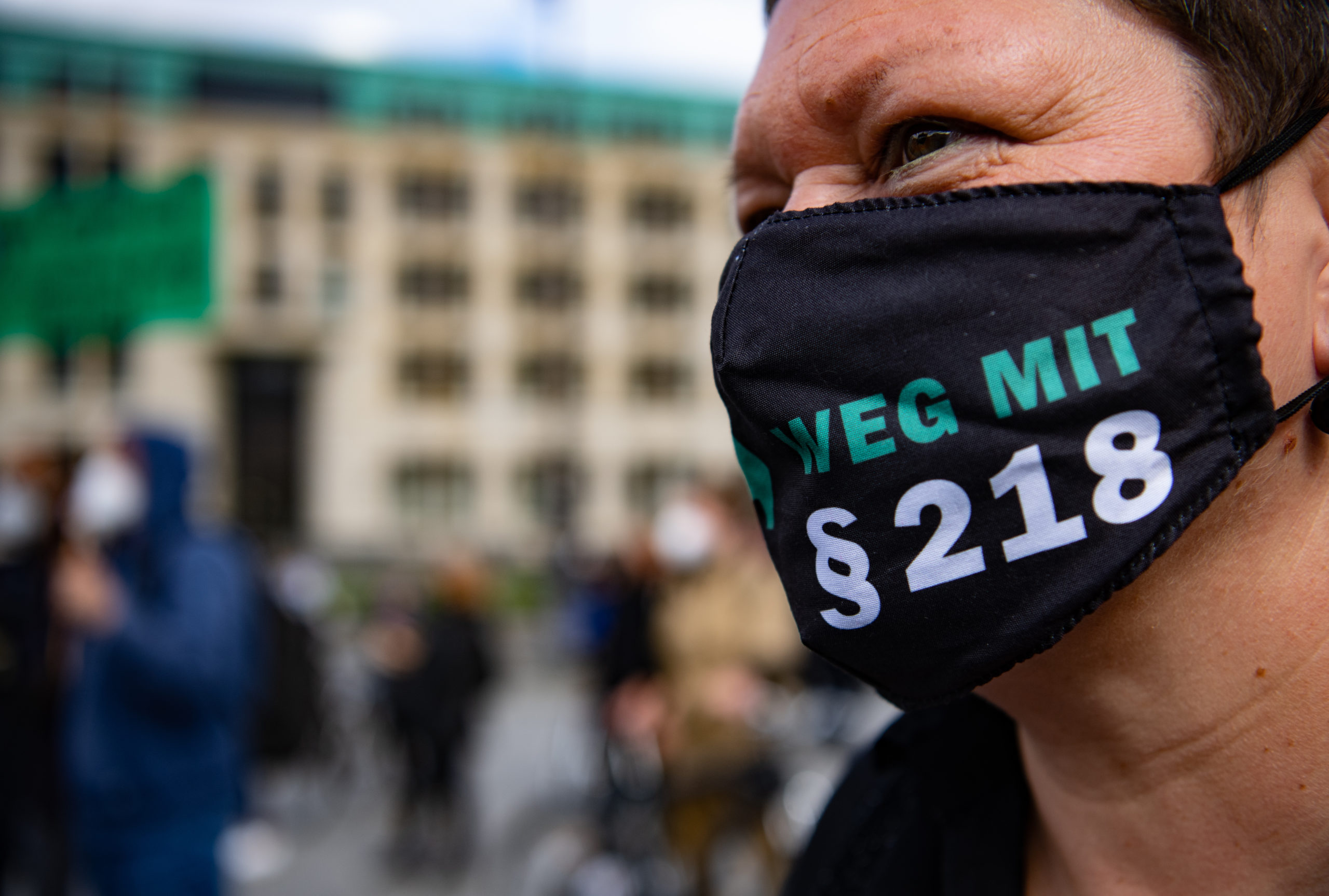 A pro-choice protester in Berlin wears a mask with "away with §218" on it.