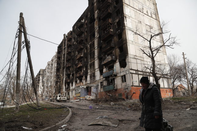 A woman walks past a burnt-out building in Mariupol, Ukraine