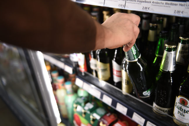 A man gets a bottle of beer from a refrigerator in a late-night shop in Berlin-Mitte.