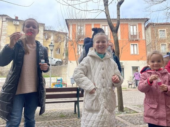 Three of Serrastretta's nine Ukrainian children blow bubbles in one of the town's piazzas. 