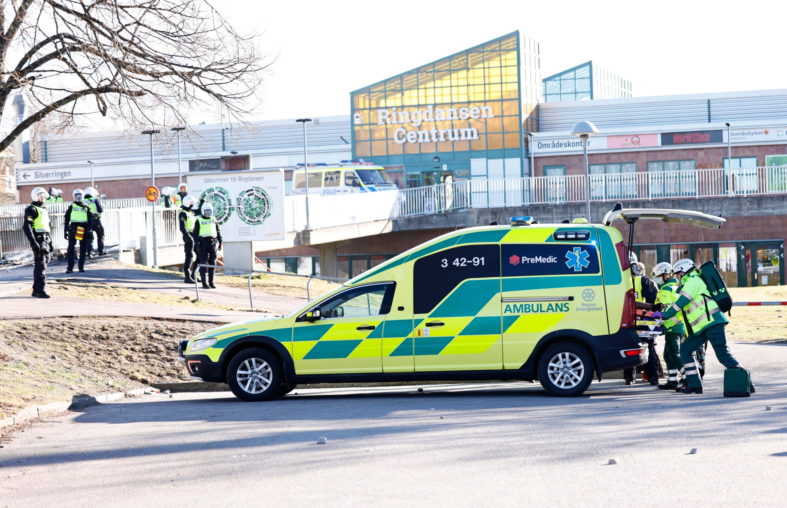Police and ambulance personnel take care of an injured man who was shot in the leg during the riots in Navestad in Norrköping on Easter 