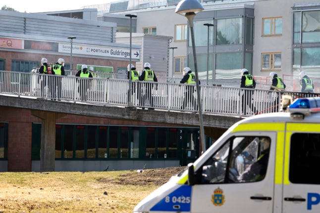Riot-equipped police pass a barricade at the centre of Ringdansen during the riots in Navestad in Norrköping on Easter day, 2022.