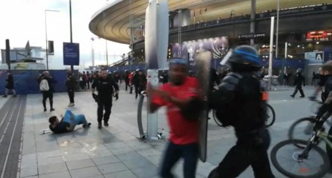 A French police officer, dressed in riot gear, shoves a fan with his shield. Many accuse the authorities of being too heavy handed in their handling of Saturday's match.