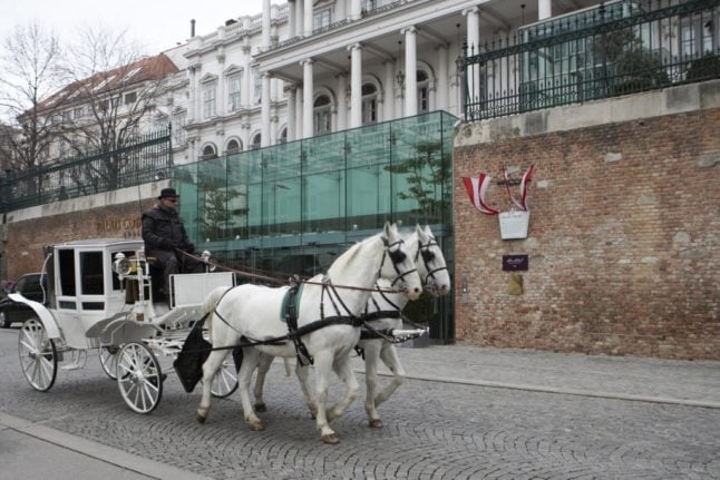 A Fiaker hackney carriage drives past the Hotel Palais Coburg,