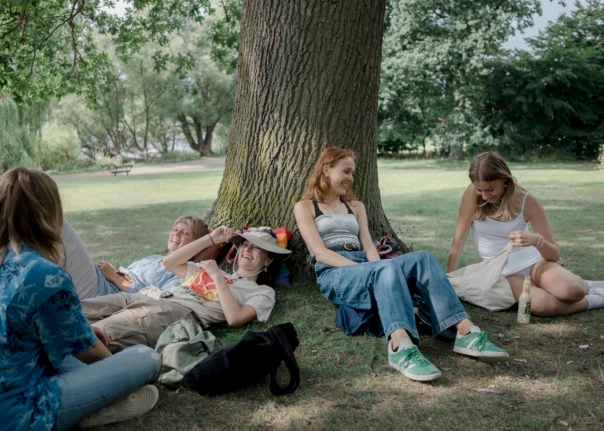Danish high school students lounge under a tree in Gentofte.