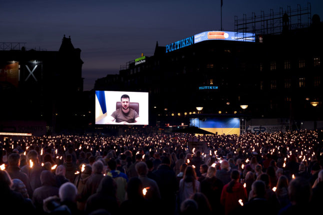 Ukrainian President Volodymyr Zelensky appears on screen to address people at the City Hall Square in Copenhagen