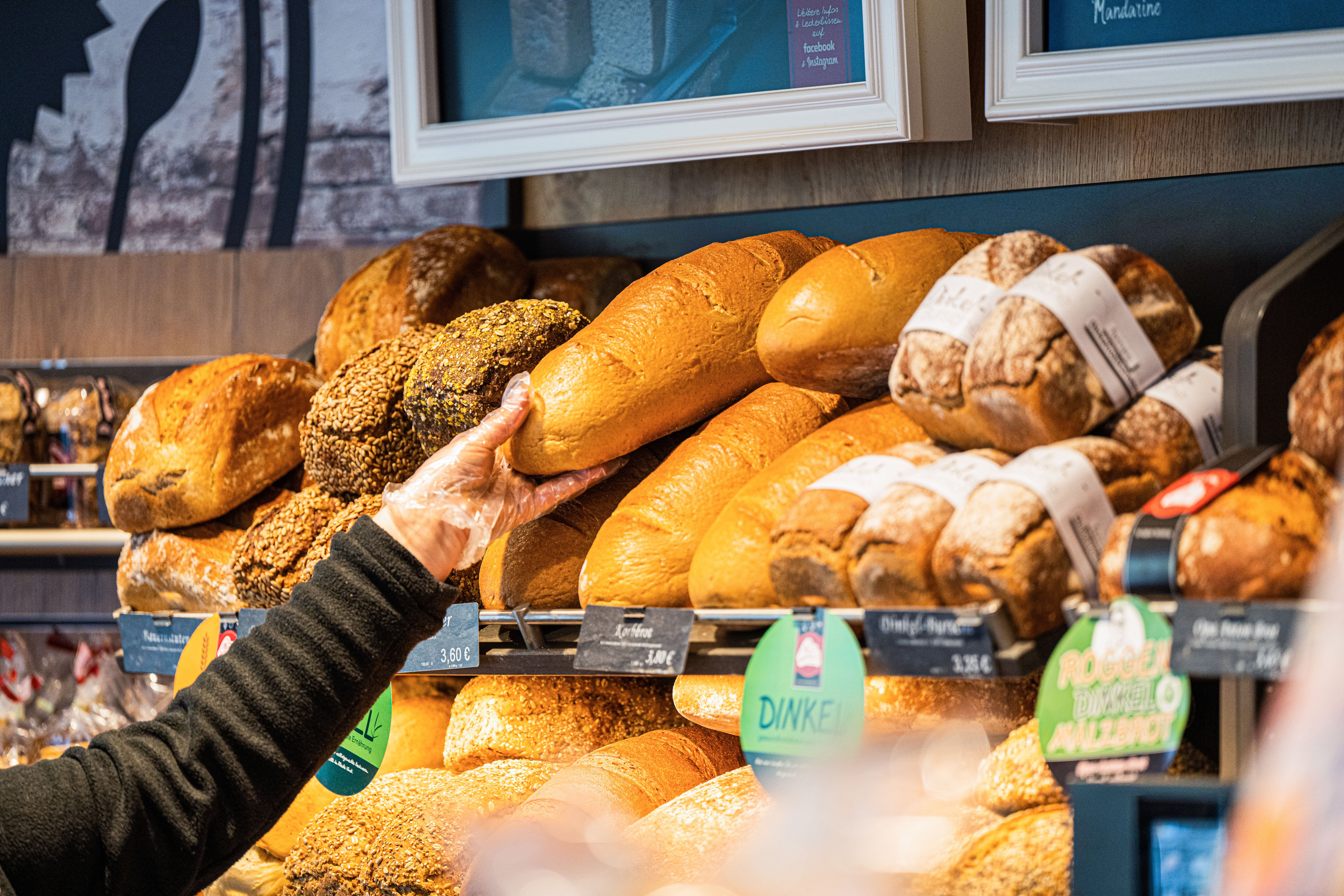 A saleswoman reaches for a loaf of bread in a bakery.