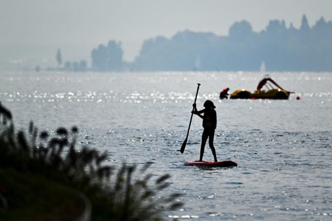 A stand-up paddler sails on Lake Constance (Bodensee) in front of Überlingen, while the Hörne leisure complex in Constance can be seen in the background.