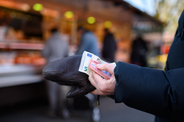 A customer holds cash in a shop in Hamburg. Germans are seeing a huge rise in the cost of living.