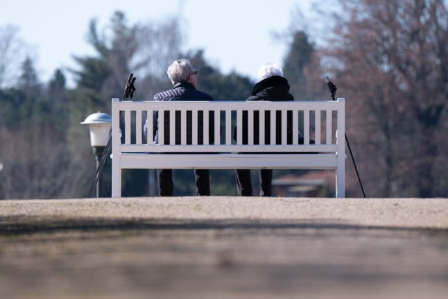 Two older people sit on a bench in Dresden, Saxony.