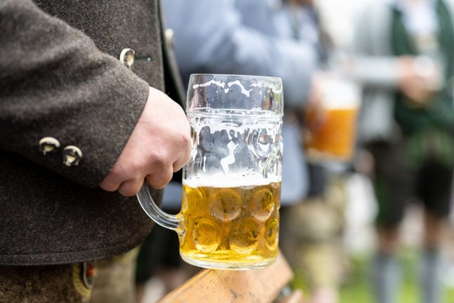 A man holds a beer during May 1st celebrations in Perchting, Bavaria.