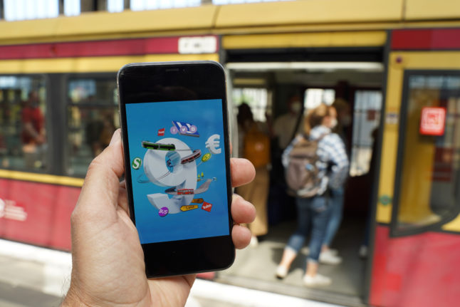 A smartphone shows an ad for the €9 ticket in front of an S-Bahn train in Berlin