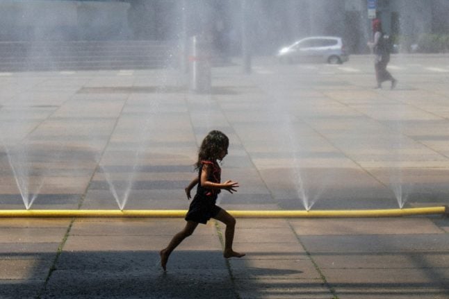A girl plays in a sprinkler.