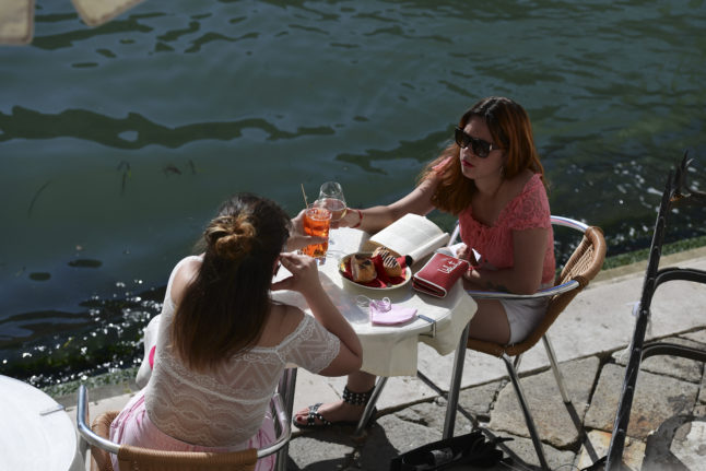 People enjoy an aperitivo drink by the Grand Canal in Venice.