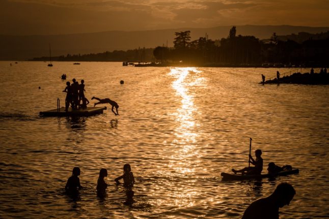 A boy jumps into Lake Geneva at sunset from a platform off the village of Lutry, western Switzerland on August 9th 2020.