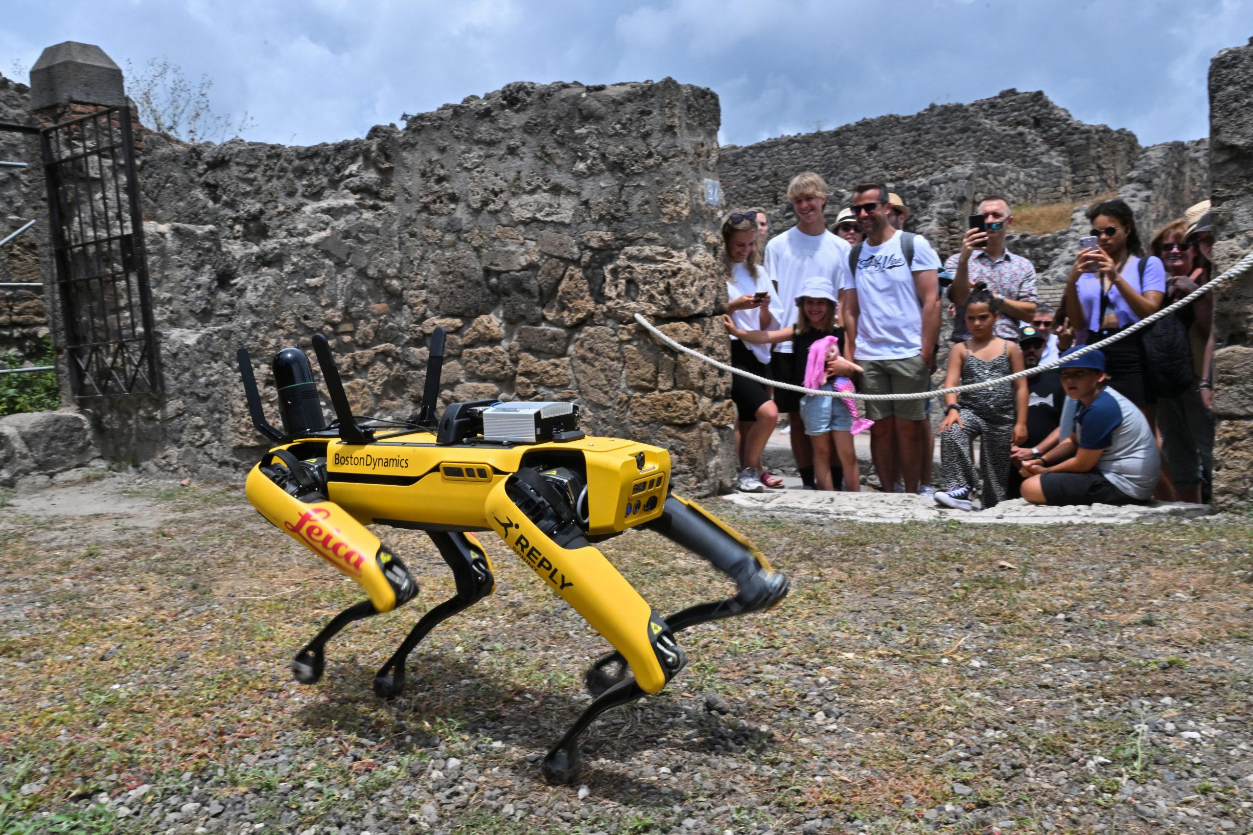 Visitors to Pompeii take photos of Spot the robot. 