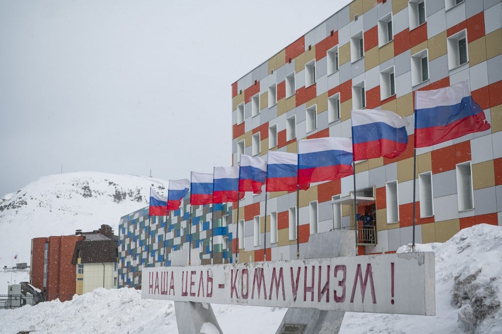 In this file photo a sign in Russian reading 'Communism is our goal' is pictured in front of a building with Russian flags flapping in the blizzard, in the miners' town of Barentsburg, on the Svalbard Archipelago, northern Norway. 