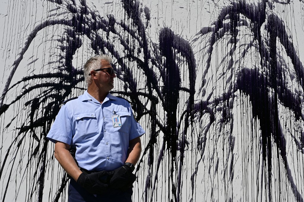 A policeman stands guard in front of a sprayed portion of the Chancellery wall.