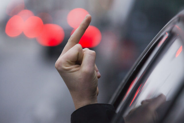 A person gives the middle fingers from a car.