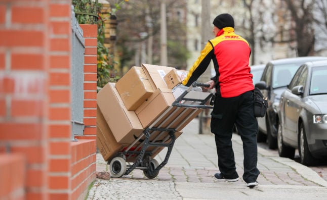 A DHL delivery worker carries packages. 
