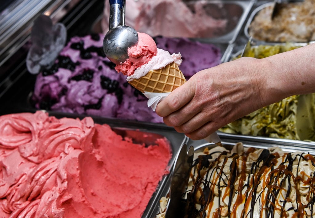 A scoop of strawberry ice cream is placed on top of another scoop in a waffle cone at the "Eiskultur" ice cream parlor in Schöneweide. 