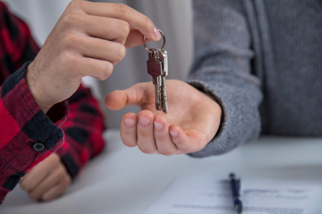 A man hands over a set of apartment keys to someone else.