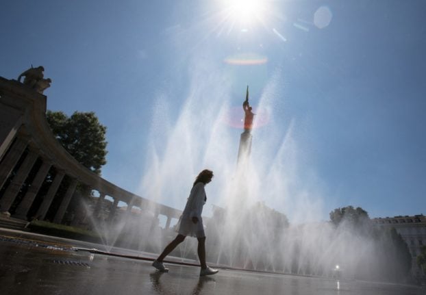 A woman walks past a fountain in Vienna