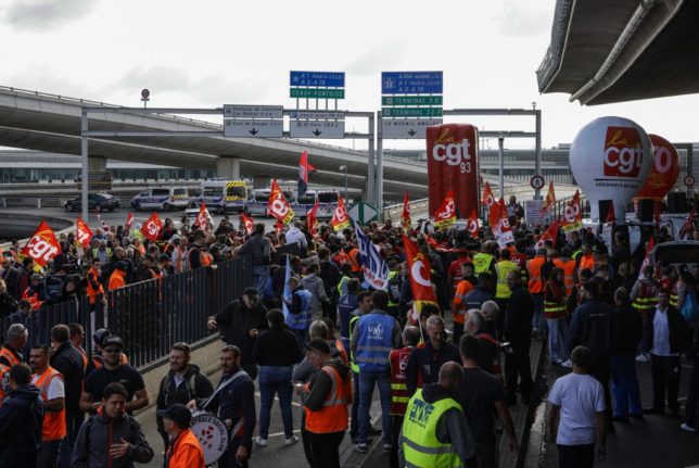 Paris Charles de Gaulle airport employees congregate outside a terminal as they stage a strike to demand higher wages at Roissy Charles De Gaulle Airport