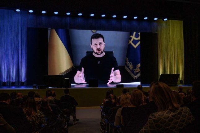 Ukraine's President Volodymyr Zelensky appears on a giant screen as he delivers a statement at the start of a two-day International conference on reconstruction of Ukraine, in Lugano on July 4, 2022. Photo: FABRICE COFFRINI / AFP
