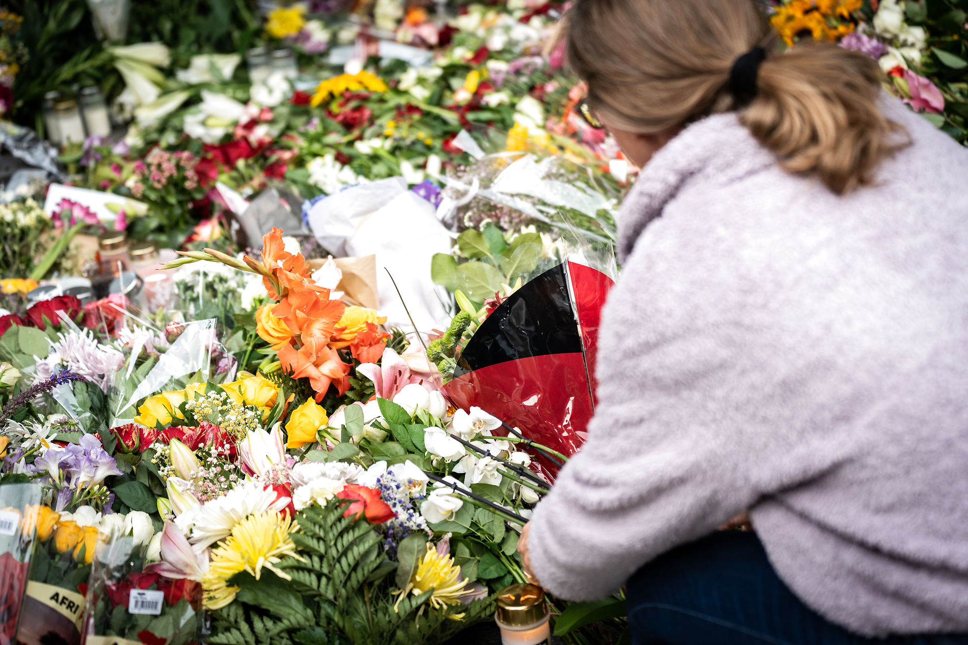 A woman lays flowers before a memorial service in front of the shopping centre Field's in Copenhagen where a shooting took place. July 5th, 2022.