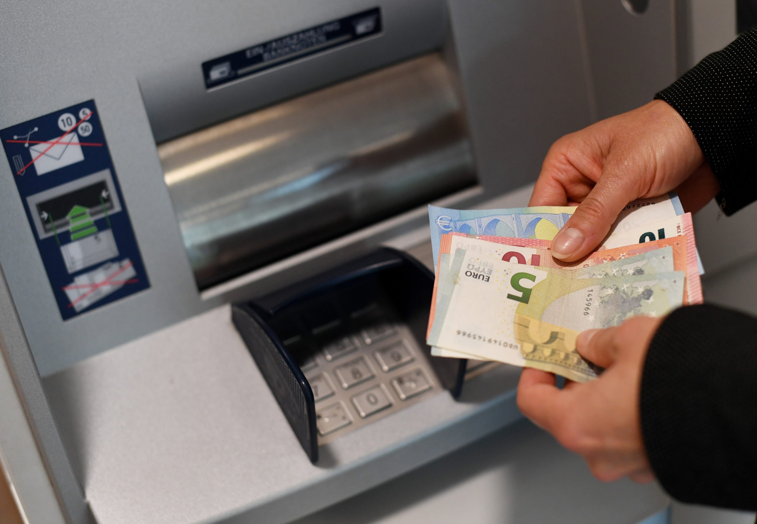 A person holds cash from an ATM machine in Germany. The country is facing tough economic times.