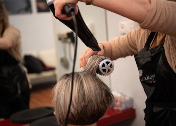 A hairdresser blow dries her customer's hair.