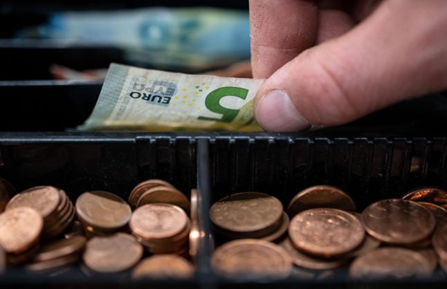 An employee takes money from the till at a shop in Stuttgart.