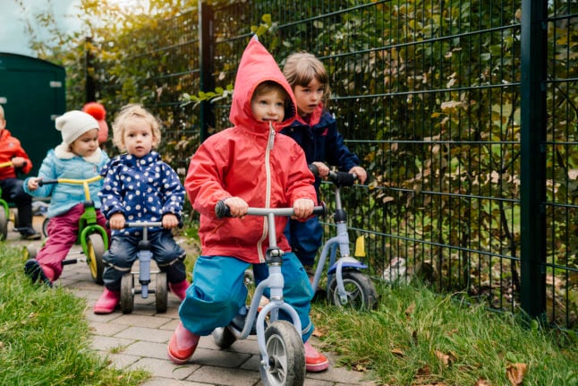 Children ride tricycles at a German kindergarten. 