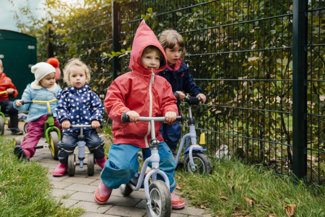 Children ride tricycles at a German kindergarten. 