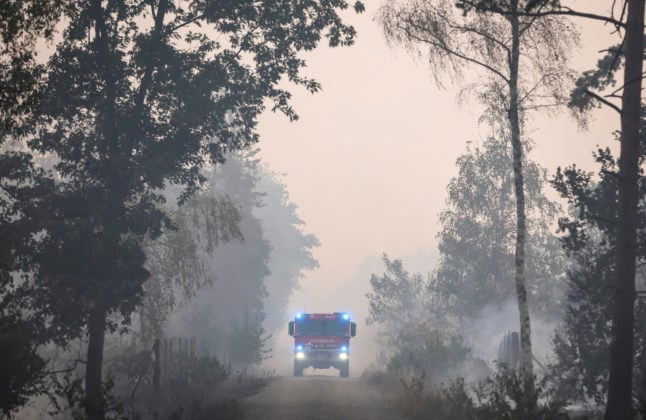 A fire truck drives over a smoky path during a forest fire in Brandenburg.