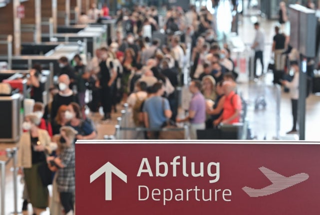 Travellers wait at a check-in for their departure from the capital's airport Berlin Brandenburg (BER).
