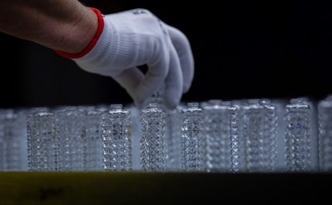 An employee inspects flacons on an assembly line at the German glass producer Heinz-Glas Group in Kleintettau, Germany on August 3rd, 2022.