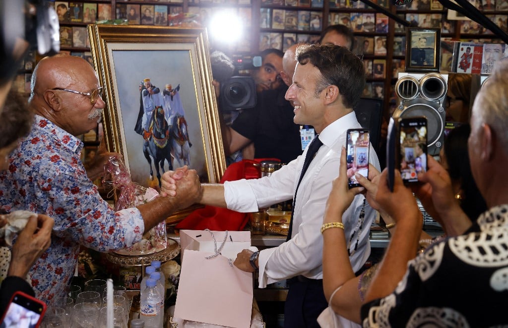 France's President Emmanuel Macron (R) shakes hands with Boualem Benhaoua (L), owner of the disco Maghreb Shopin
