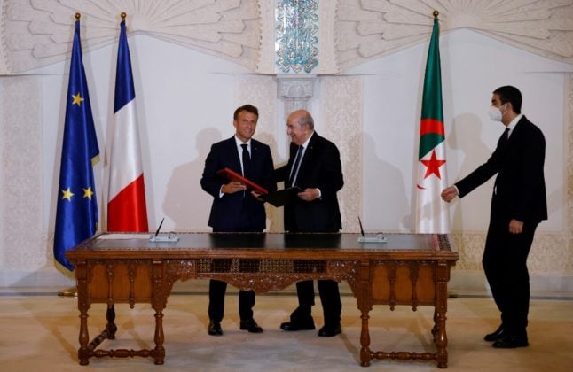 French President Emmanuel Macron (L) and Algeria's President Abdelmadjid Tebboune shake hands in Algeria