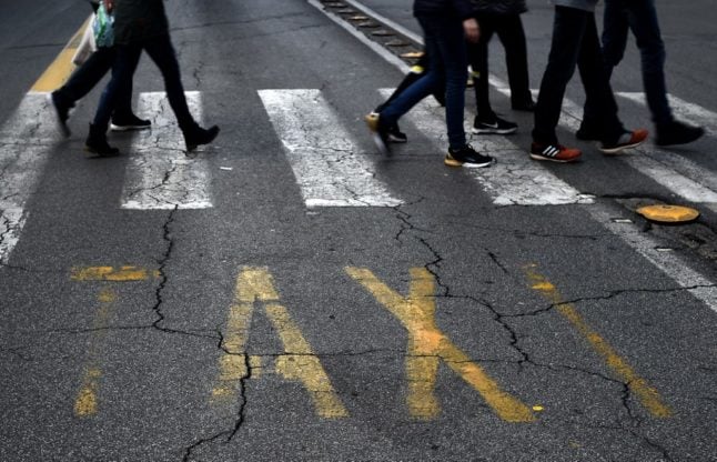 Pedestrians walk on an empty taxi lane in central Rome, Italy