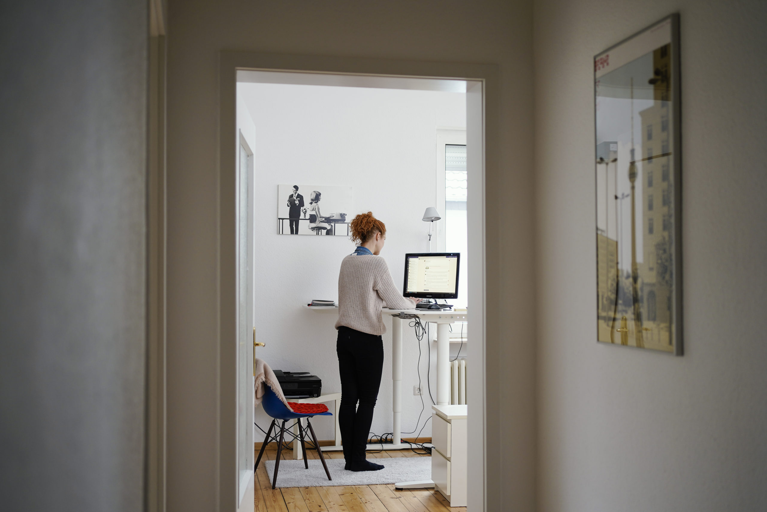 A woman uses her kitchen worktop as a standing desk while working from home.