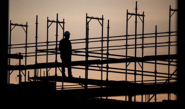 The silhouette of a construction worker stands out against the morning sky at a building site in Hannover.
