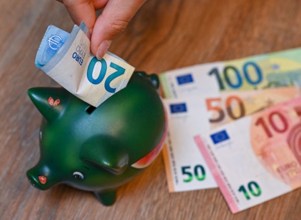 A person places money in a piggy bank in Germany.