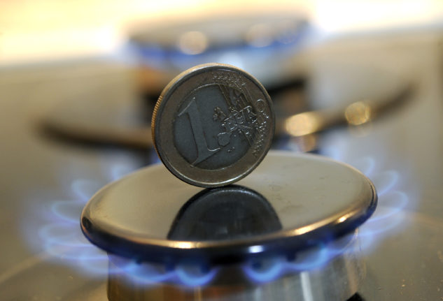 A one-euro coin stands between the flames of a gas-powered cooker.