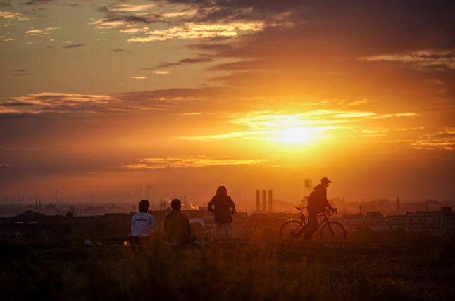 People watch the sunrise over Berlin on the Drachenberg on August 3rd.
